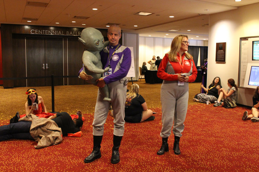 Quiet, the baby is sleeping as Alexander Dane and Gwen DeMarco from Galaxy Quest tiptoe through a back hallway.